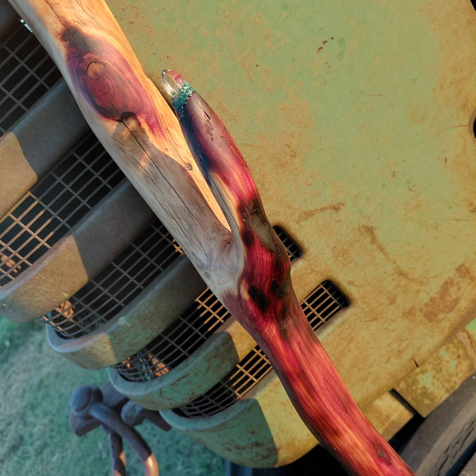 A finished eastern red cedar wand resting on the hood of an old green tractor
