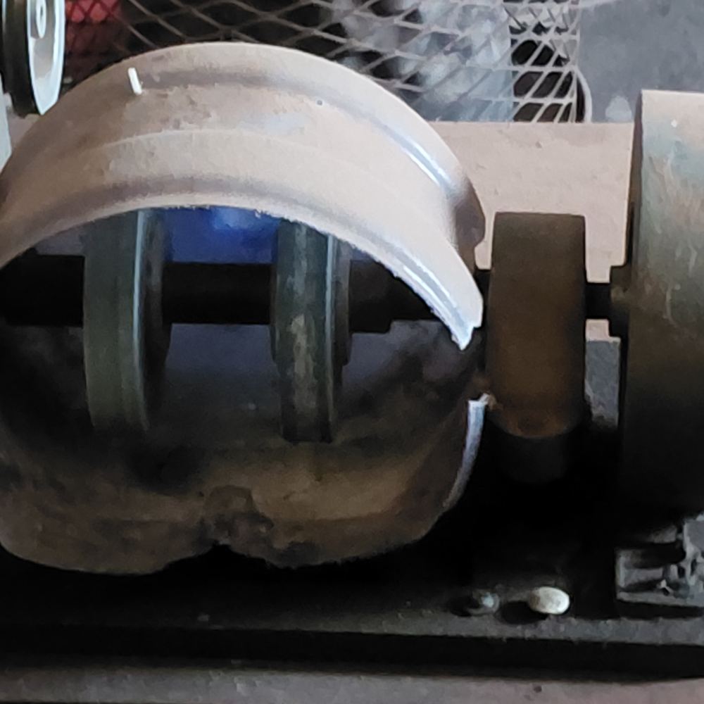 Close view of a lapidary grinding wheel with a curved guard cut from recycled plastic fitted around it.